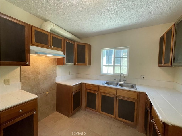 kitchen featuring sink, tile countertops, a textured ceiling, and light tile patterned floors