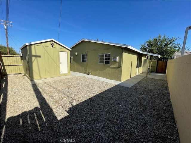 rear view of property with a patio area and a storage unit