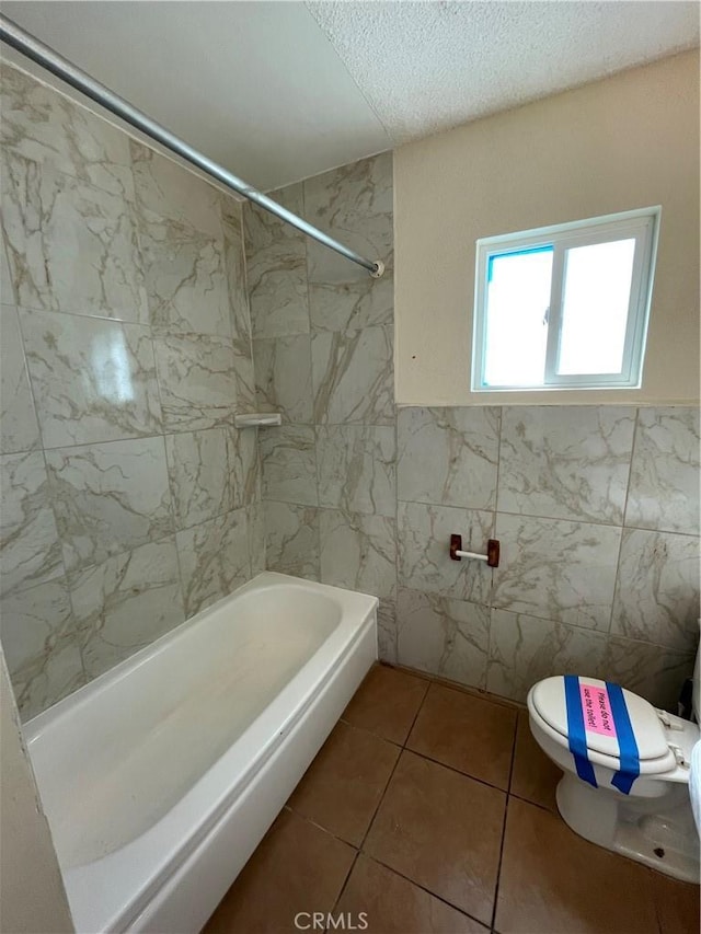 bathroom featuring tile patterned floors, toilet, tile walls, and tiled shower / bath