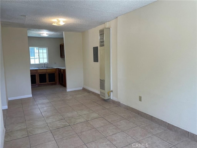 tiled empty room featuring sink, a textured ceiling, and electric panel