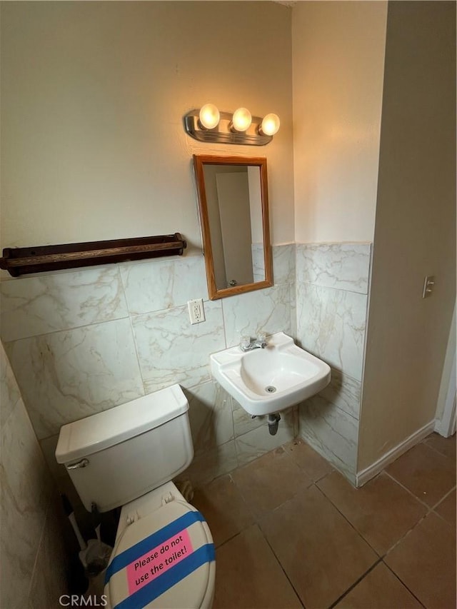 bathroom featuring sink, toilet, tile walls, and tile patterned flooring