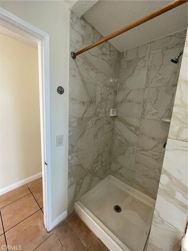 bathroom featuring a tile shower, a textured ceiling, and tile patterned flooring