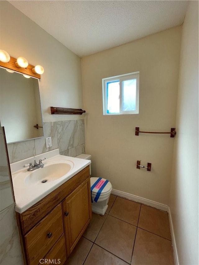 bathroom featuring toilet, a textured ceiling, tile patterned flooring, and vanity