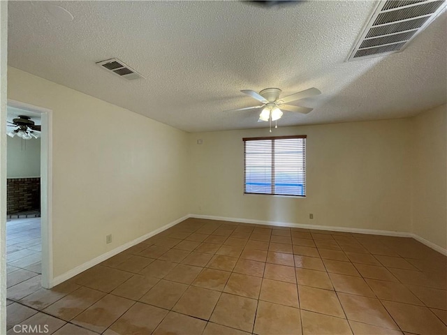 spare room with a textured ceiling, light tile patterned floors, and ceiling fan