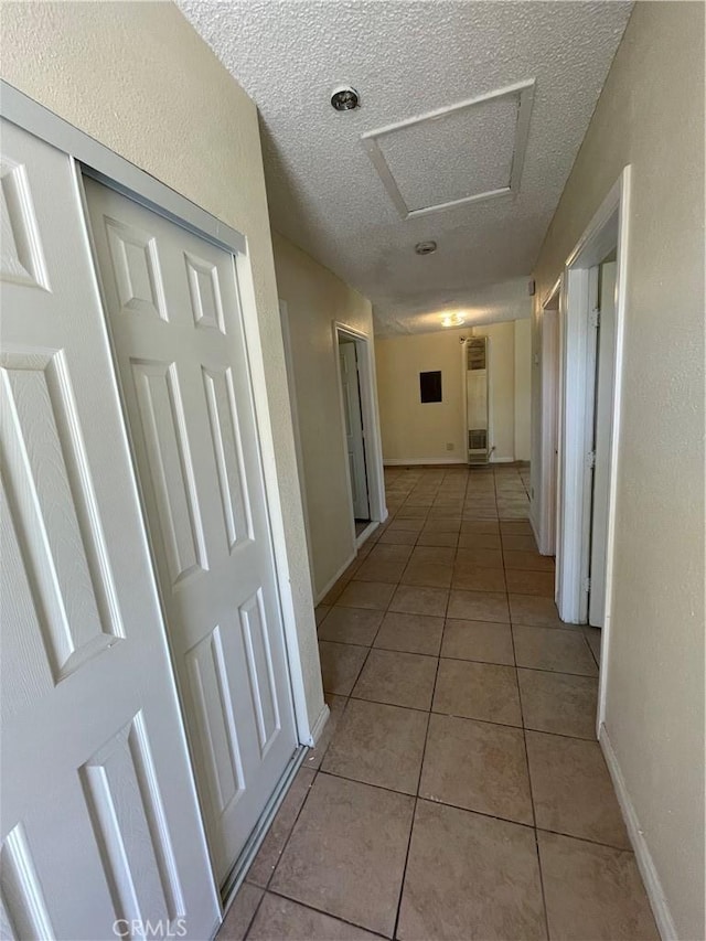 hall with a textured ceiling and light tile patterned flooring