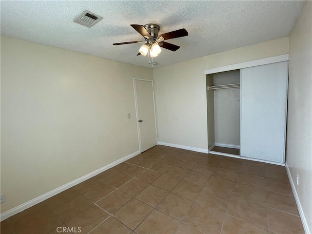 unfurnished bedroom featuring a textured ceiling, a closet, tile patterned flooring, and ceiling fan