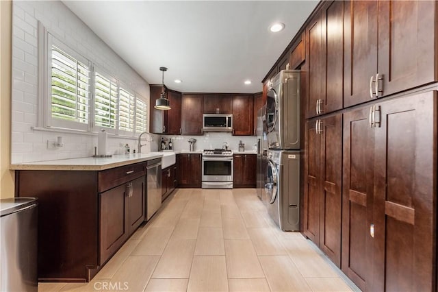 kitchen with decorative light fixtures, stainless steel appliances, decorative backsplash, stacked washer / drying machine, and sink