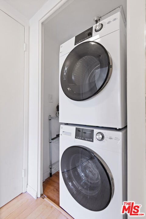 laundry room featuring light wood-type flooring and stacked washer and clothes dryer