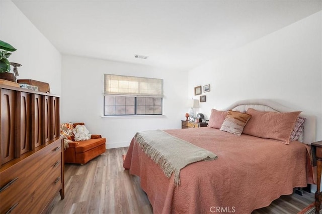 bedroom featuring visible vents, baseboards, and wood finished floors