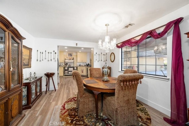 dining room featuring an inviting chandelier and light wood-type flooring