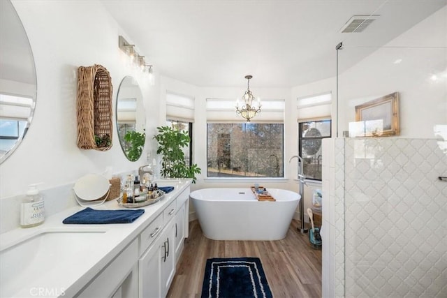 bathroom with vanity, hardwood / wood-style floors, an inviting chandelier, and plus walk in shower