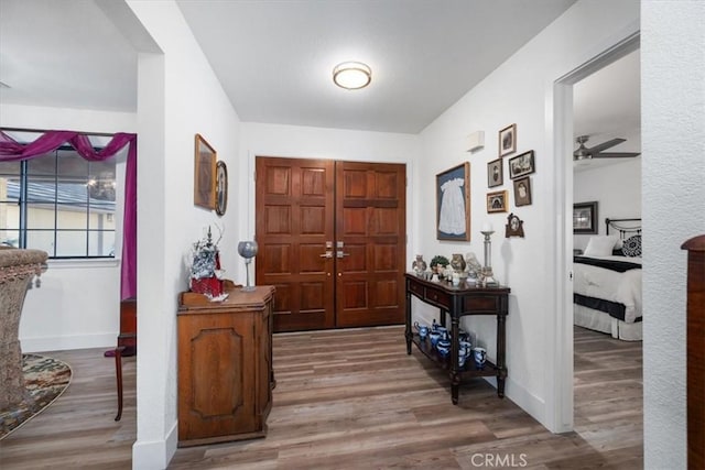 foyer with a ceiling fan, baseboards, and wood finished floors