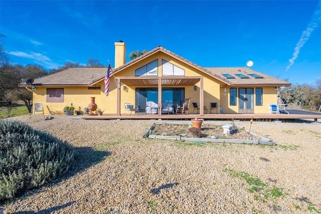 back of property with a deck and solar panels