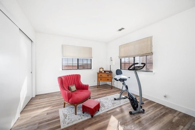 workout area with baseboards, visible vents, and wood finished floors