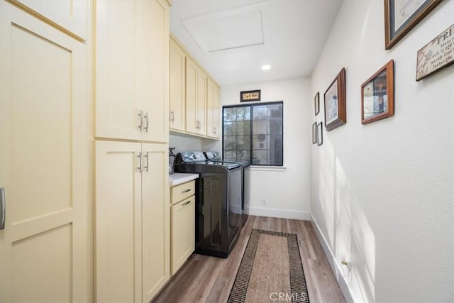 clothes washing area featuring baseboards, wood finished floors, recessed lighting, washing machine and dryer, and cabinet space