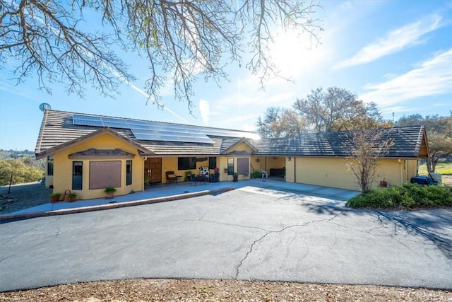 1885 Nacimiento Lake Dr, Paso Robles, CA 93446 - ranch-style house with driveway, roof mounted solar panels, stucco siding, a tiled roof, and a garage