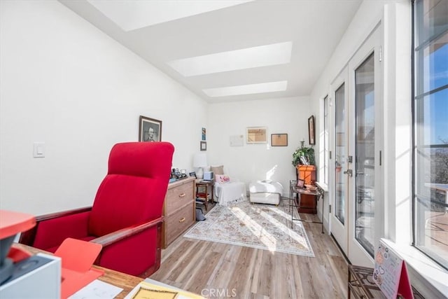 home office featuring wood finished floors, french doors, a skylight, and plenty of natural light