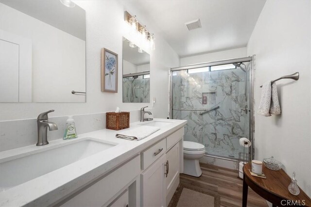 bathroom with vanity, a shower with shower door, toilet, and wood-type flooring