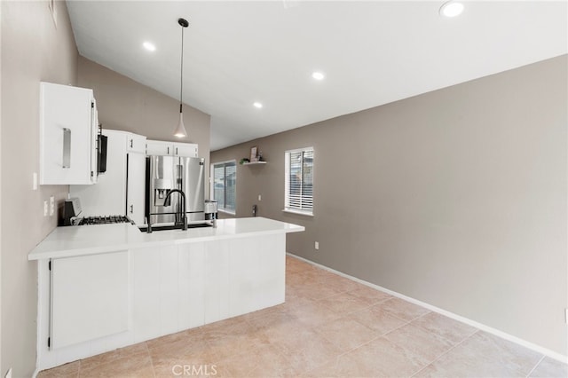 kitchen featuring pendant lighting, stove, kitchen peninsula, sink, and stainless steel fridge