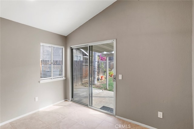 tiled empty room featuring lofted ceiling