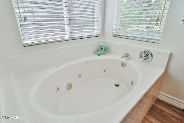 bathroom featuring hardwood / wood-style flooring and tiled tub