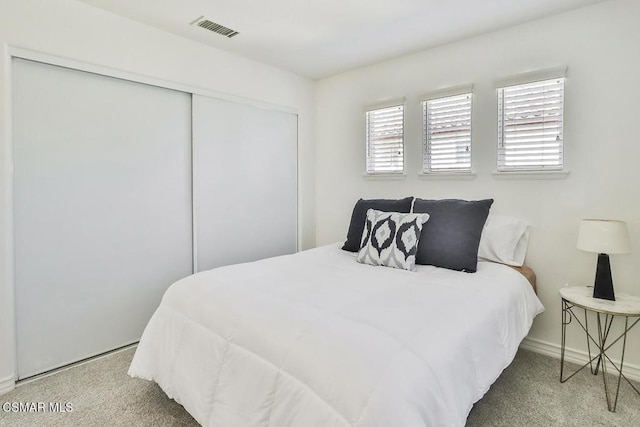 carpeted bedroom with a closet and multiple windows