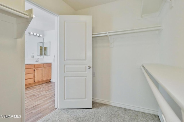 spacious closet featuring light colored carpet and sink