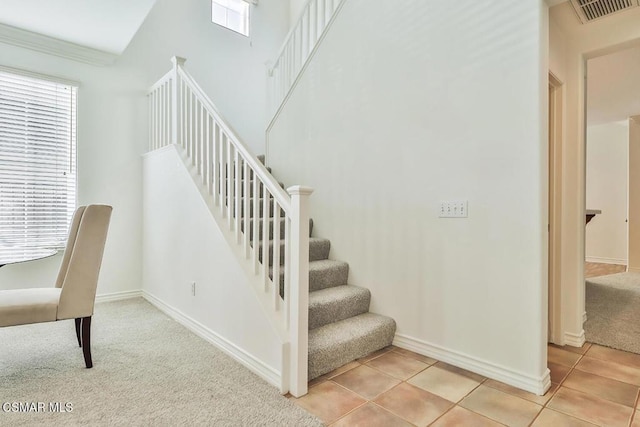 stairs with tile patterned flooring and crown molding