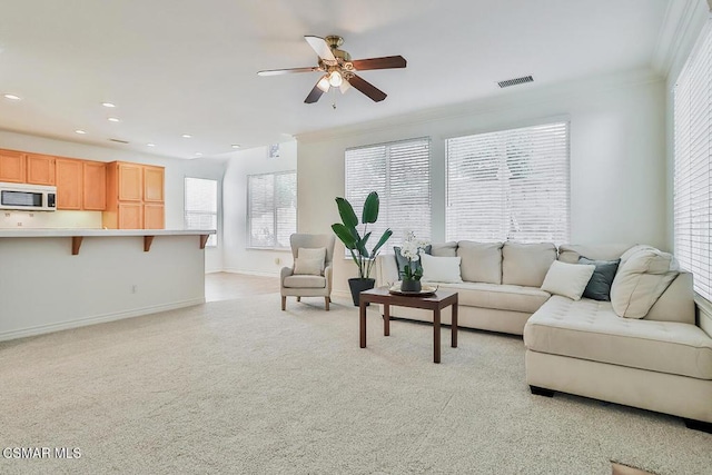 carpeted living room featuring ceiling fan, a healthy amount of sunlight, and ornamental molding