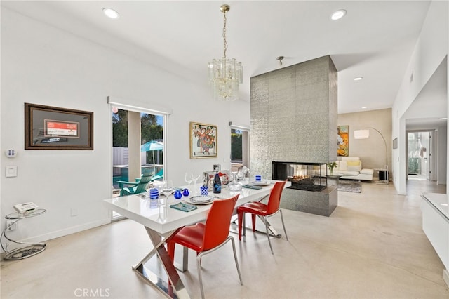 dining area featuring a high ceiling, a notable chandelier, and a tiled fireplace