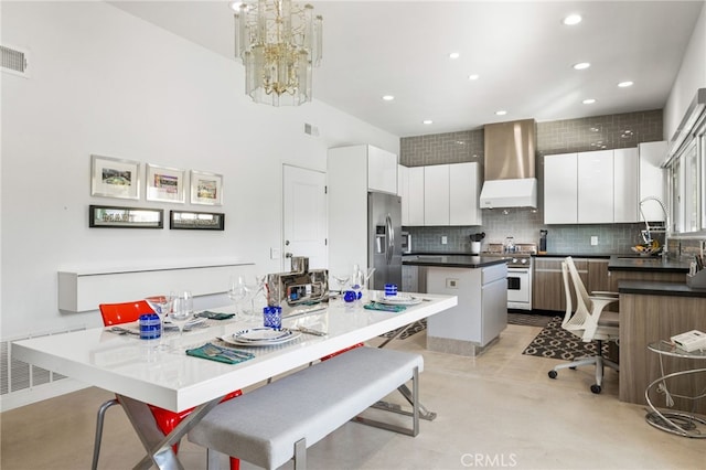 kitchen featuring white cabinetry, stainless steel refrigerator with ice dispenser, high end white range oven, a kitchen island, and wall chimney exhaust hood