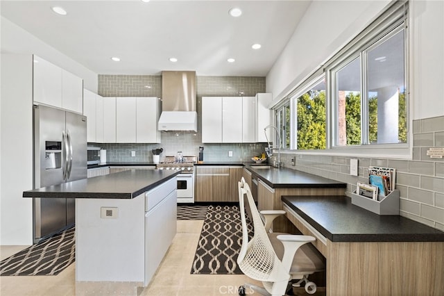 kitchen featuring high end white range oven, wall chimney exhaust hood, white cabinets, and sink