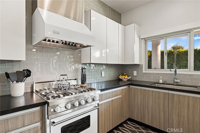 kitchen with white cabinetry, decorative backsplash, wall chimney range hood, stainless steel stove, and sink