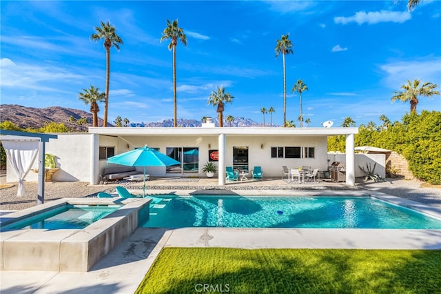 back of property featuring a mountain view, a pool with hot tub, and a patio