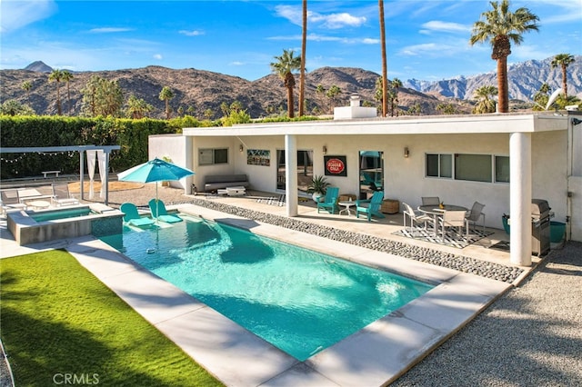 view of swimming pool featuring a patio area, a mountain view, and an in ground hot tub