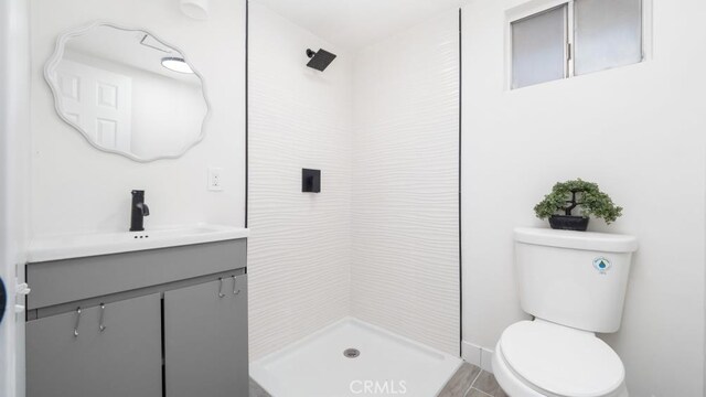 bathroom featuring vanity, toilet, and tiled shower