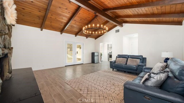 living room featuring a chandelier, wood ceiling, a stone fireplace, and lofted ceiling with beams