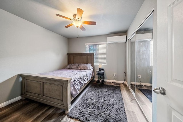 bedroom featuring an AC wall unit, wood-type flooring, a closet, and ceiling fan