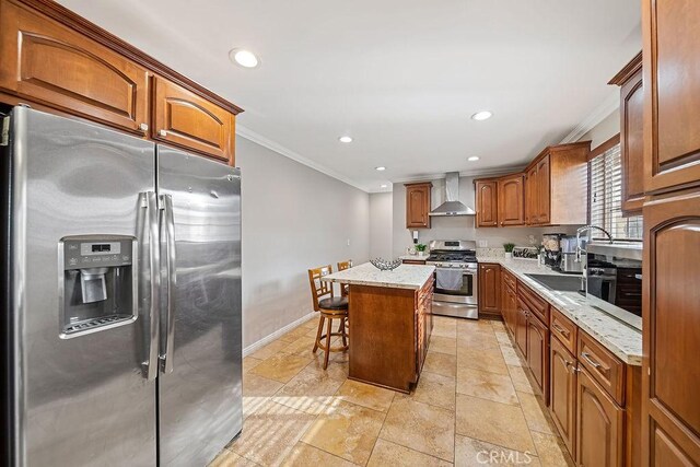 kitchen with appliances with stainless steel finishes, a center island, wall chimney exhaust hood, crown molding, and a breakfast bar area