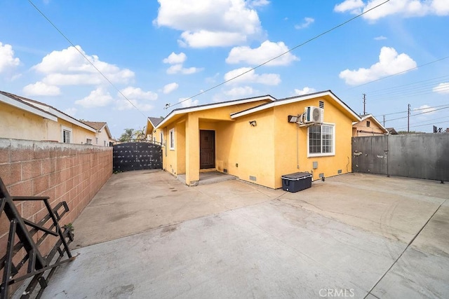 rear view of property with a patio area and an AC wall unit