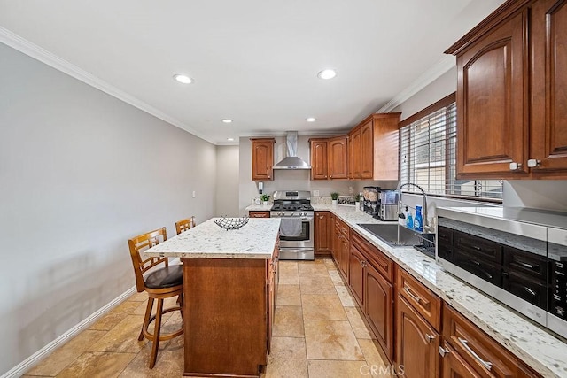 kitchen with a center island, wall chimney range hood, sink, gas range, and a breakfast bar area