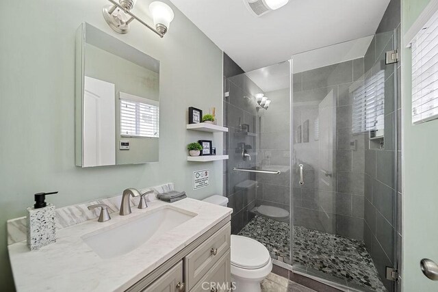 bathroom featuring toilet, vanity, and an enclosed shower