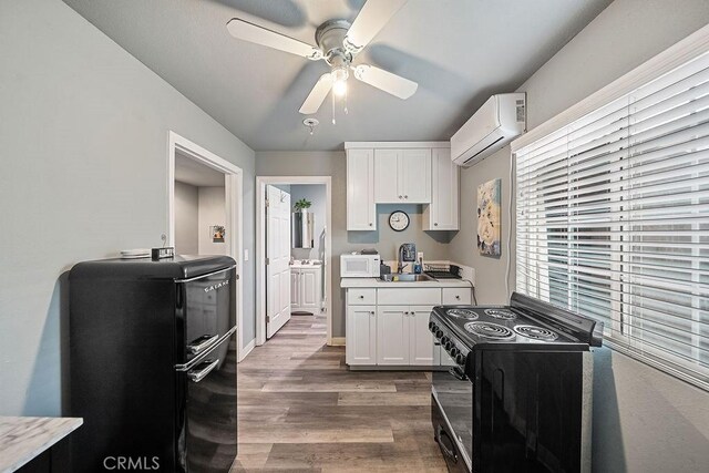 6220 Alamo Ave, Bell, CA 90201 - kitchen with white cabinetry, ceiling fan, a wall mounted air conditioner, dark wood-type flooring, and black appliances