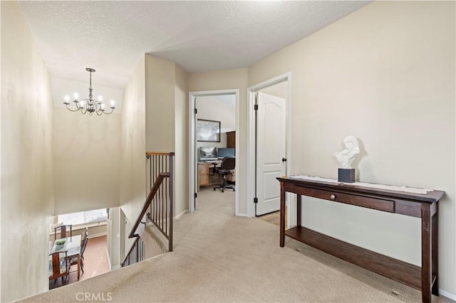 hallway featuring light carpet, a chandelier, and a textured ceiling