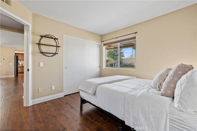 bedroom with dark hardwood / wood-style floors and black refrigerator