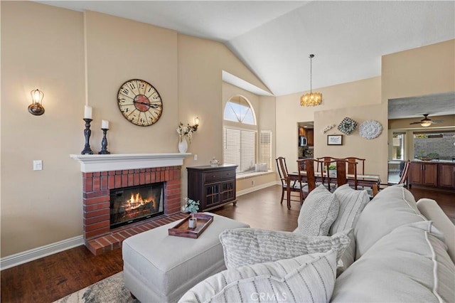 living room with ceiling fan with notable chandelier, dark hardwood / wood-style floors, lofted ceiling, and a fireplace