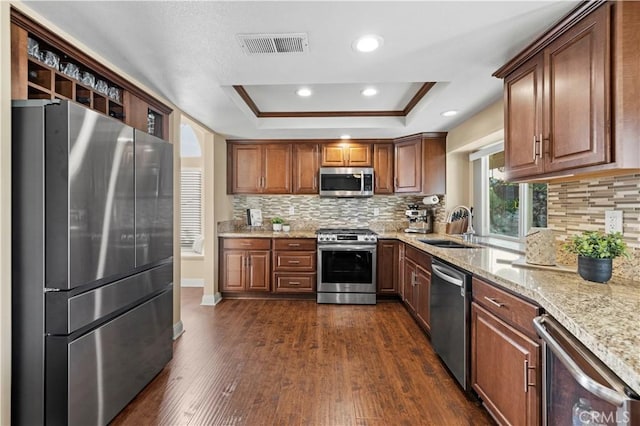 kitchen with stainless steel appliances, a raised ceiling, tasteful backsplash, dark hardwood / wood-style flooring, and sink