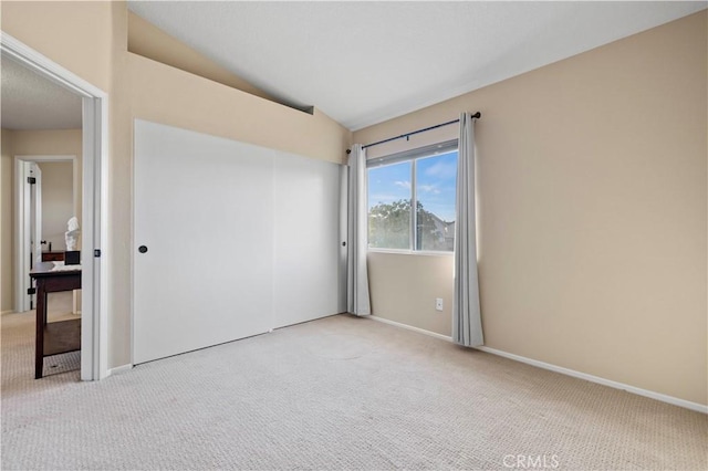 unfurnished bedroom with vaulted ceiling and light colored carpet