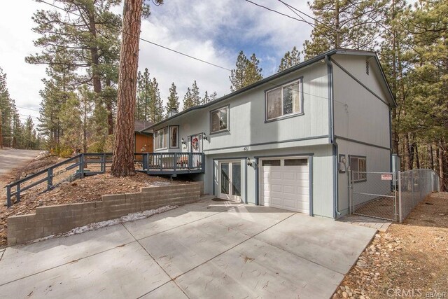 rear view of property featuring a garage and a wooden deck