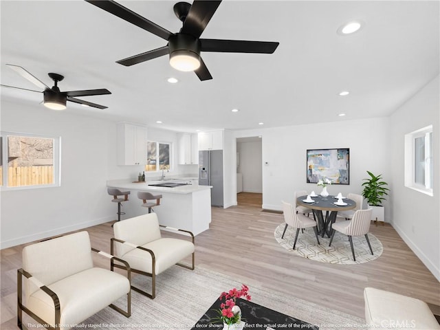 living room with light hardwood / wood-style floors, ceiling fan, and sink